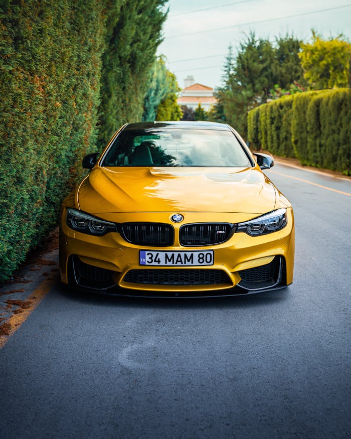 Front view of a striking yellow car parked on a lush green street in Ankara, Türkiye.