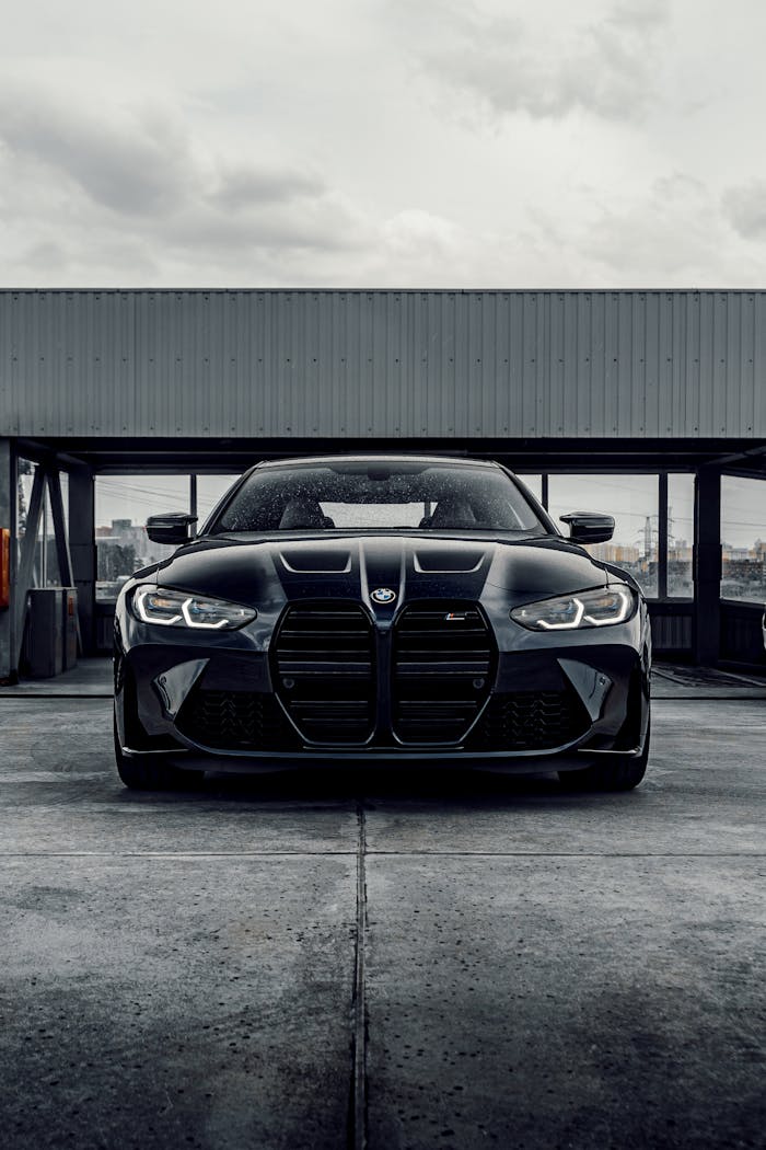 About A sleek black luxury car parked in an industrial urban setting, showcasing modern design and elegance.